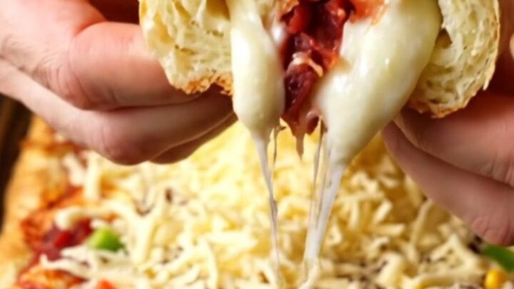 Sheet-pan breakfast pizza rolls with sucuk, corn, peppers, and melted cheese, rolled up and served on a wooden board.