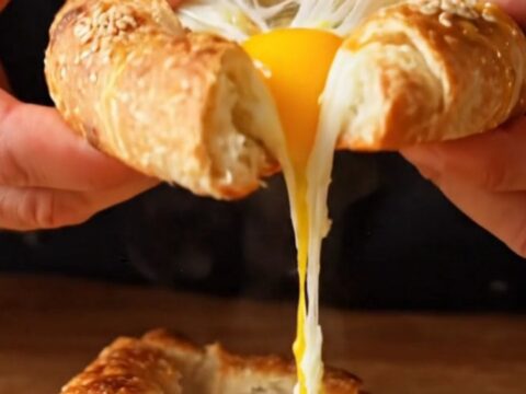 Triangular lavaş pide boat with melted cheese and a baked egg, garnished with parsley