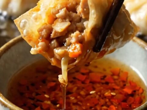 Golden crispy rice paper dumplings piled on a plate with chili crisp and soy sauce
