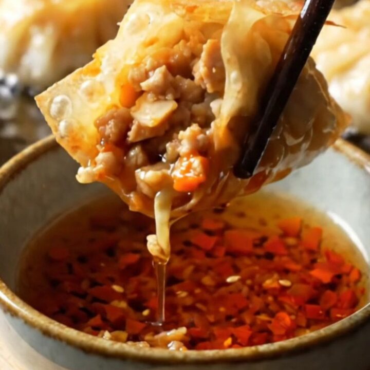 Golden crispy rice paper dumplings piled on a plate with chili crisp and soy sauce