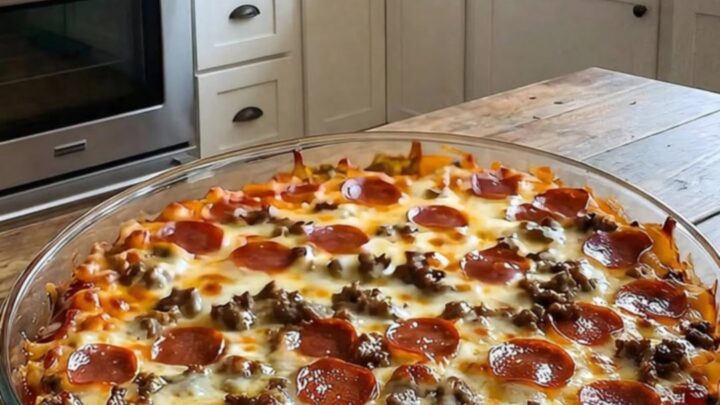 A close-up of a serving spatula lifting a portion of meat lovers pizza casserole, showing stretchy melted cheese.
