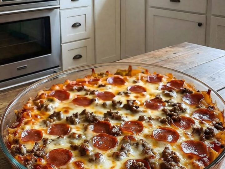 A close-up of a serving spatula lifting a portion of meat lovers pizza casserole, showing stretchy melted cheese.