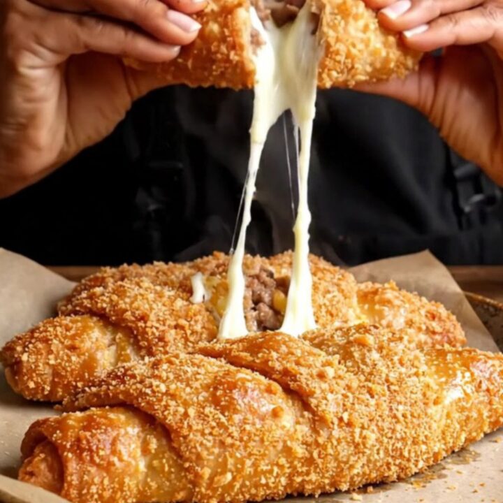Golden crispy breaded meat börek on a baking sheet, with a cross-section showing melted cheese