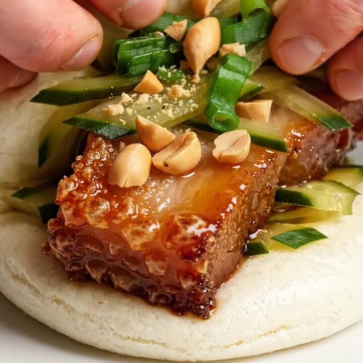 Crispy pork belly bao buns with hoisin glaze, pickled cucumbers, and peanuts