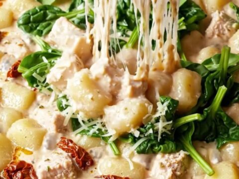 Bubbling golden casserole dish of creamy Tuscan chicken gnocchi bake with melted mozzarella and a cheese pull