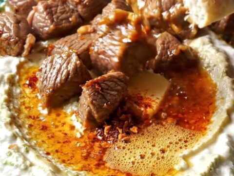 Ali Nazik kebab with sizzling lamb over creamy eggplant yogurt on a ceramic plate