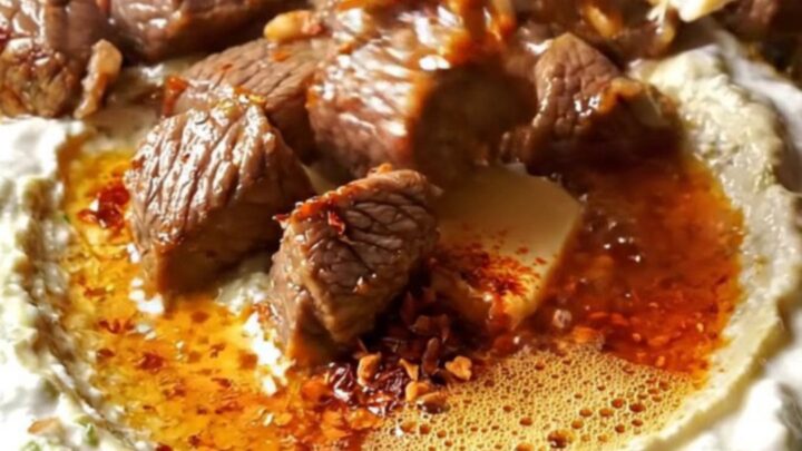 Ali Nazik kebab with sizzling lamb over creamy eggplant yogurt on a ceramic plate