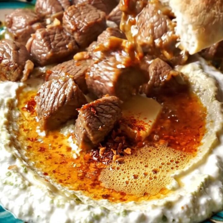 Ali Nazik kebab with sizzling lamb over creamy eggplant yogurt on a ceramic plate