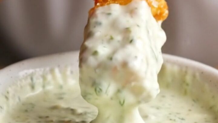 Golden accordion zucchini fries with parmesan coating, served with a bowl of herb yogurt dip.