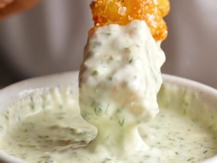 Golden accordion zucchini fries with parmesan coating, served with a bowl of herb yogurt dip.