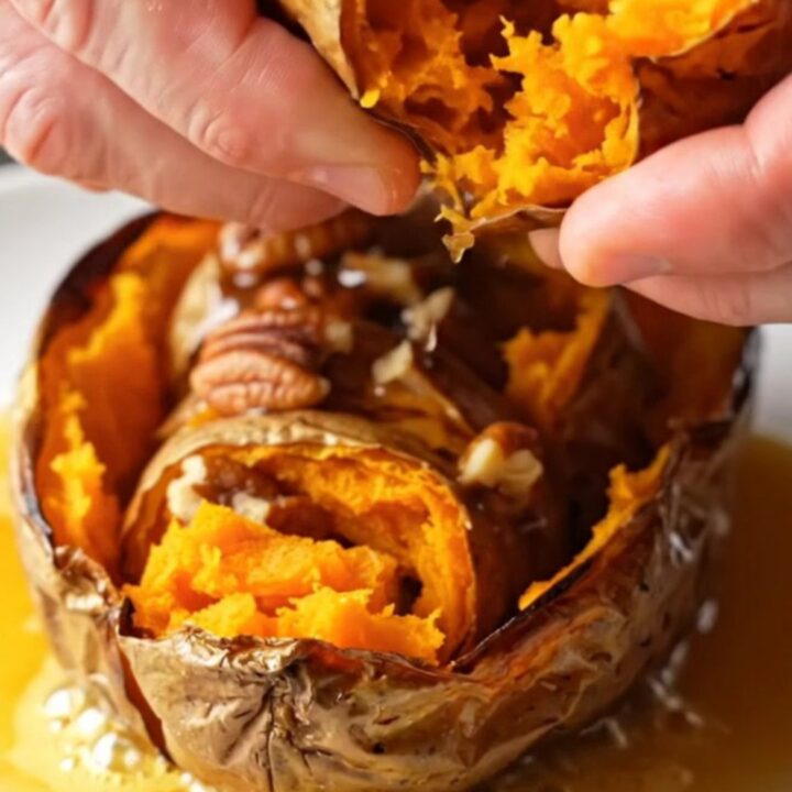 Crispy accordion sweet potatoes on a platter, drizzled with maple pecan butter