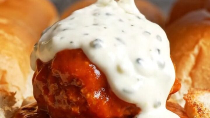 Giant buffalo chicken meatball slider pulled apart with melted mozzarella stretching between the rolls