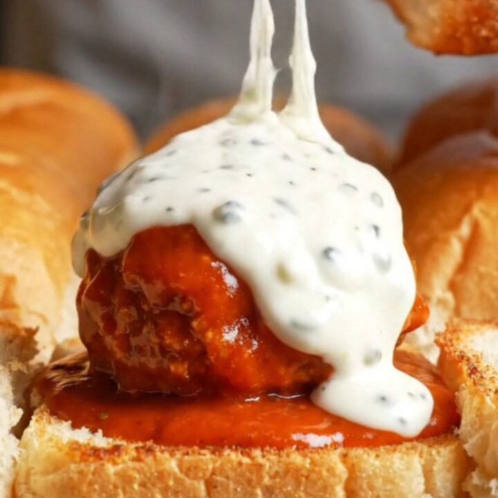 Giant buffalo chicken meatball slider pulled apart with melted mozzarella stretching between the rolls
