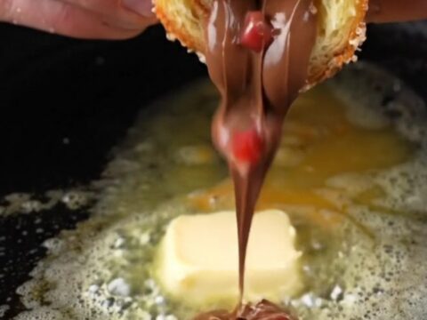 Golden French toast roll-ups coated in cinnamon sugar, with melted Nutella and strawberries oozing out