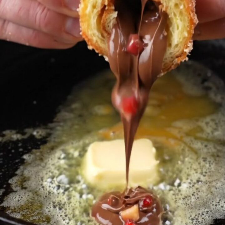 Golden French toast roll-ups coated in cinnamon sugar, with melted Nutella and strawberries oozing out