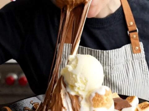 Spoon cutting through toasted marshmallows and gooey blondie in a cast iron skillet