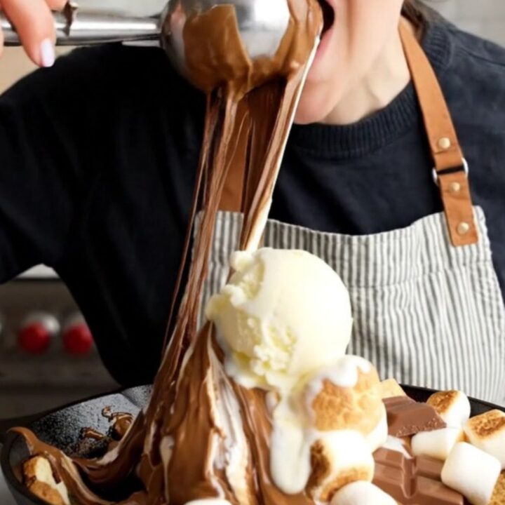 Spoon cutting through toasted marshmallows and gooey blondie in a cast iron skillet