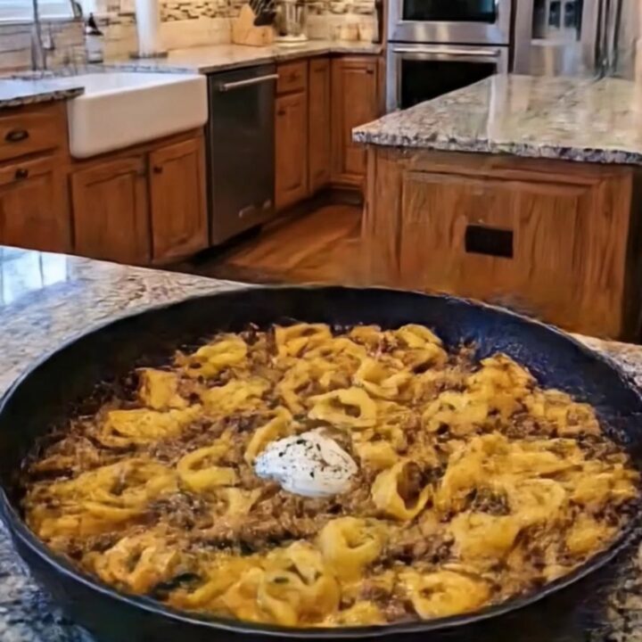 A close-up of creamy beef tortellini in a black pan with steam rising.