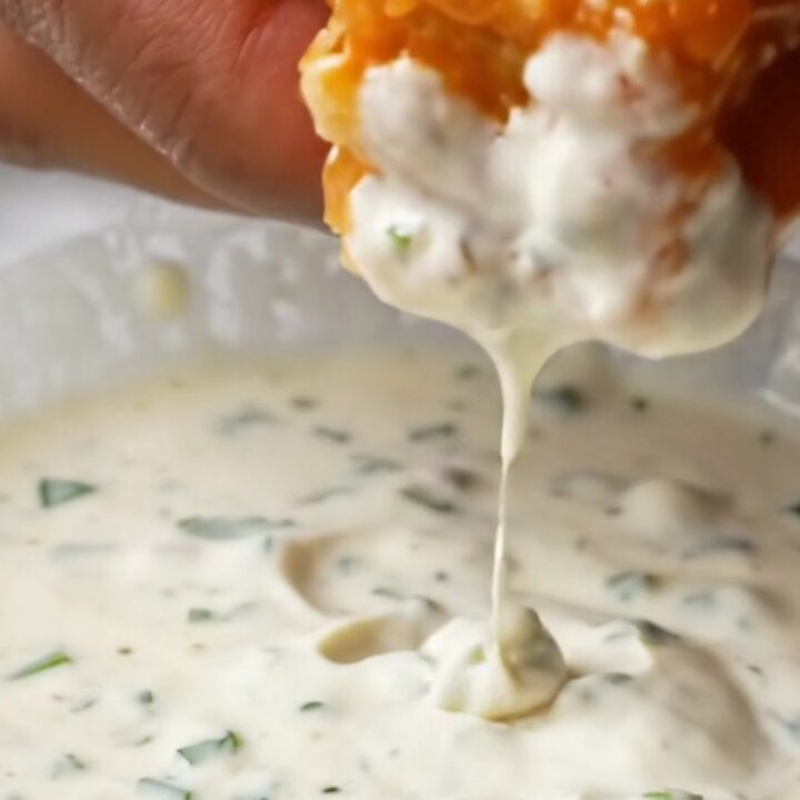 Crispy golden tofu cubes coated in glossy buffalo sauce, with a bowl of ranch and celery sticks on the side.