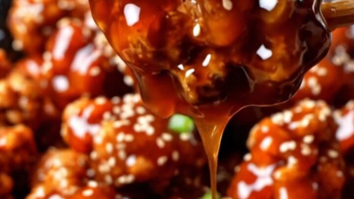 Crispy gochujang popcorn chicken in a glossy red glaze, topped with sesame seeds and scallions.