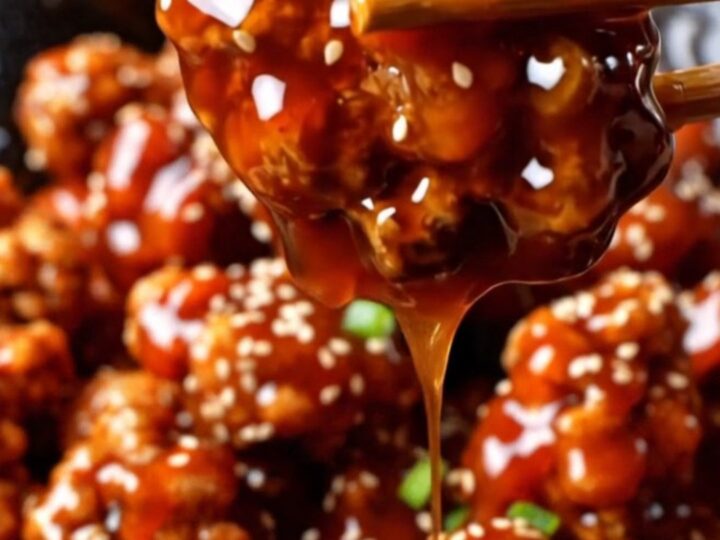 Crispy gochujang popcorn chicken in a glossy red glaze, topped with sesame seeds and scallions.