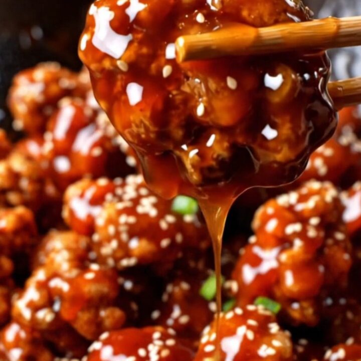 Crispy gochujang popcorn chicken in a glossy red glaze, topped with sesame seeds and scallions.