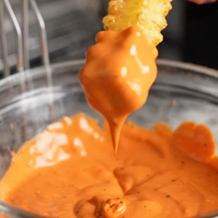 Crispy accordion rutabaga fries with smoky paprika aioli, stacked on a plate