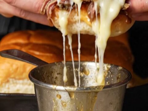 Golden French dip sliders with melted provolone and caramelized onions, served with a cup of au jus for dipping.