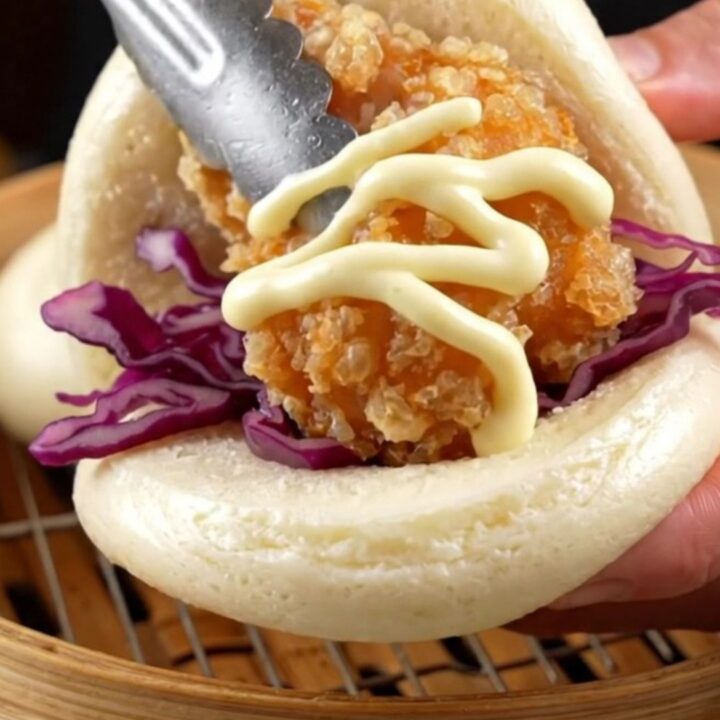 A soft steamed bao bun filled with golden crispy chicken karaage, purple cabbage, and a zigzag of Kewpie mayo.