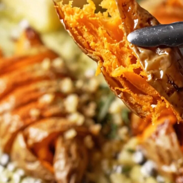 Crispy accordion sweet potatoes on a platter, drizzled with garlic herb butter