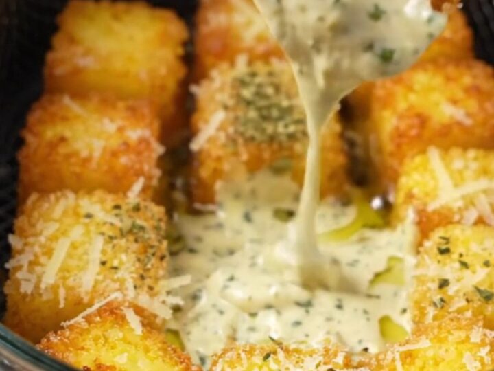 Golden crispy parmesan polenta bites on a plate with a bowl of garlic herb aioli for dipping