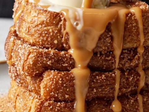 Giant stack of churro French toast topped with vanilla ice cream and dulce de leche