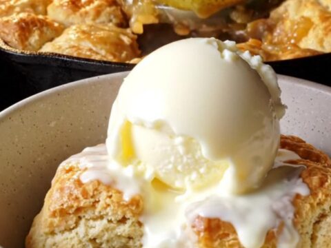 Skillet cinnamon pear cobbler with golden buttermilk biscuit topping and melting vanilla ice cream
