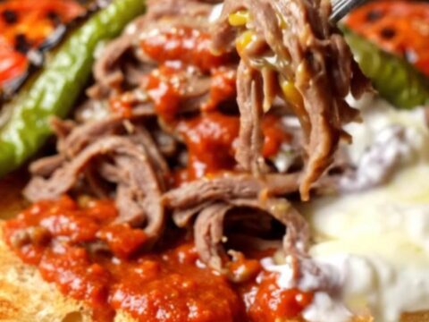 Platter of İskender kebab with shaved meat over toasted pide, tomato sauce, and foaming butter