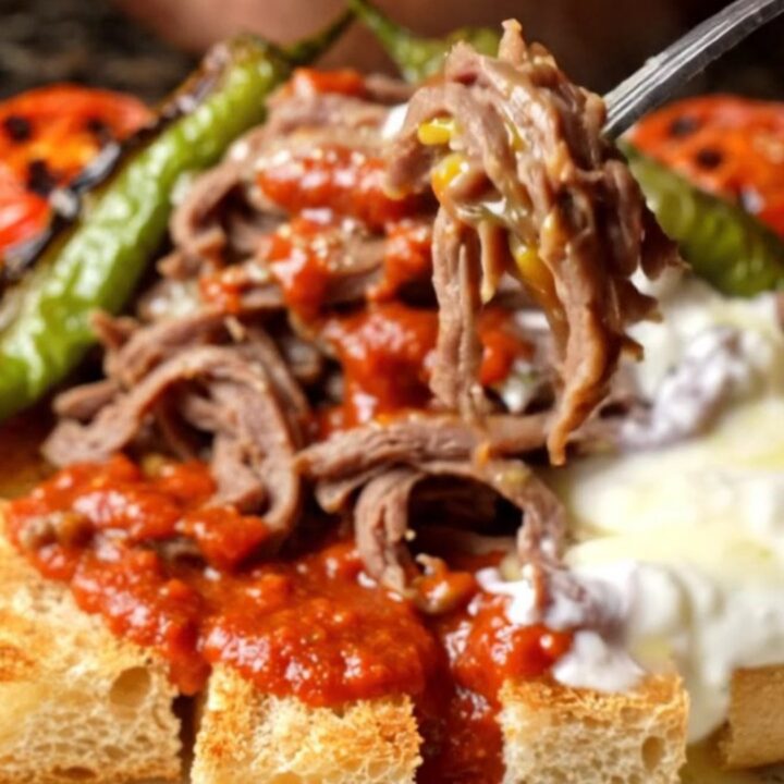 Platter of İskender kebab with shaved meat over toasted pide, tomato sauce, and foaming butter