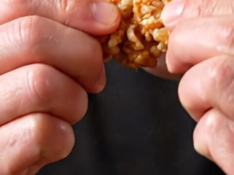 Crispy Korean soy garlic popcorn chicken bites in a black bowl, glistening with glaze and sprinkled with sesame seeds