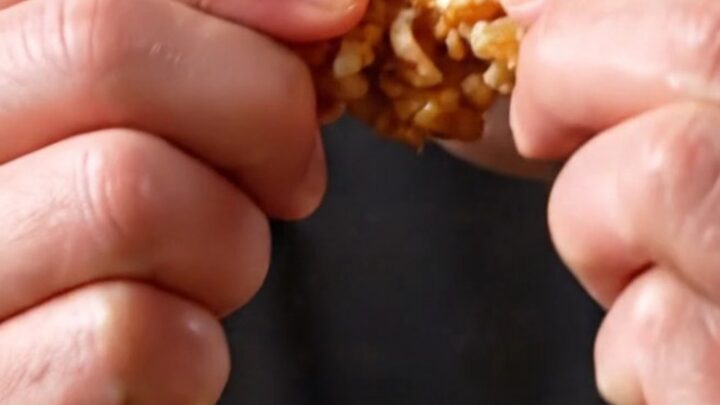 Crispy Korean soy garlic popcorn chicken bites in a black bowl, glistening with glaze and sprinkled with sesame seeds