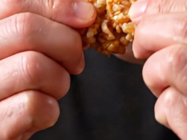 Crispy Korean soy garlic popcorn chicken bites in a black bowl, glistening with glaze and sprinkled with sesame seeds