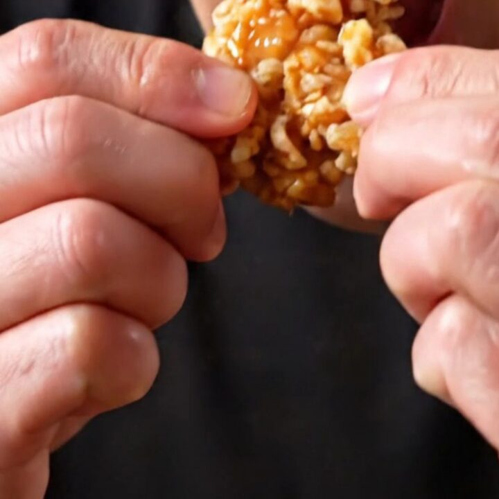 Crispy Korean soy garlic popcorn chicken bites in a black bowl, glistening with glaze and sprinkled with sesame seeds