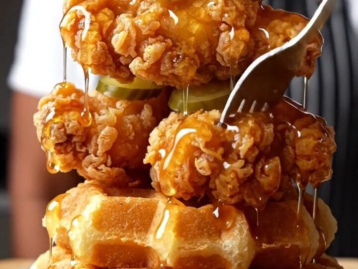 Crispy Nashville hot chicken tenders stacked on waffles with pickles and honey
