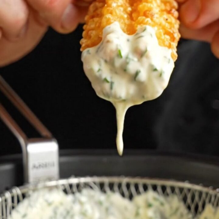 Crispy accordion zucchini fries with golden edges, served with a bowl of creamy herb aioli.