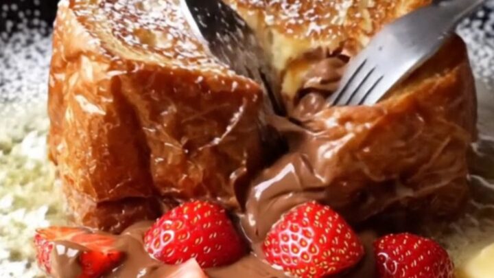 Giant stuffed Nutella brioche French toast cut open showing molten Nutella and strawberries