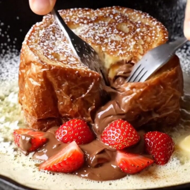Giant stuffed Nutella brioche French toast cut open showing molten Nutella and strawberries