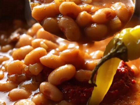 A clay pot of Turkish kuru fasulye with white beans and pastırma in rich red sauce, served over butter rice pilaf