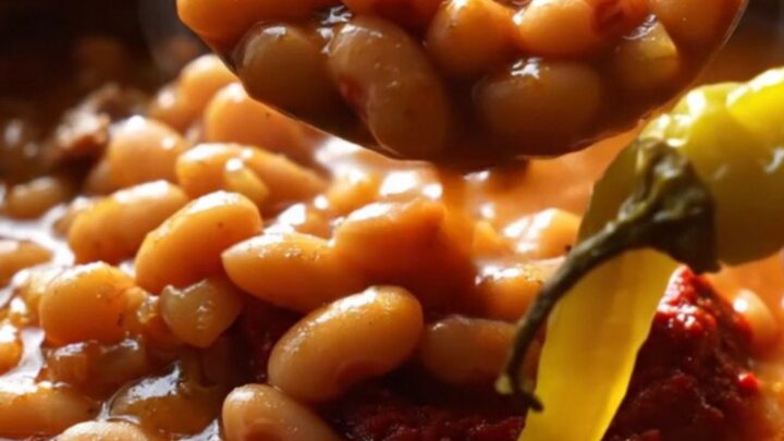 A clay pot of Turkish kuru fasulye with white beans and pastırma in rich red sauce, served over butter rice pilaf