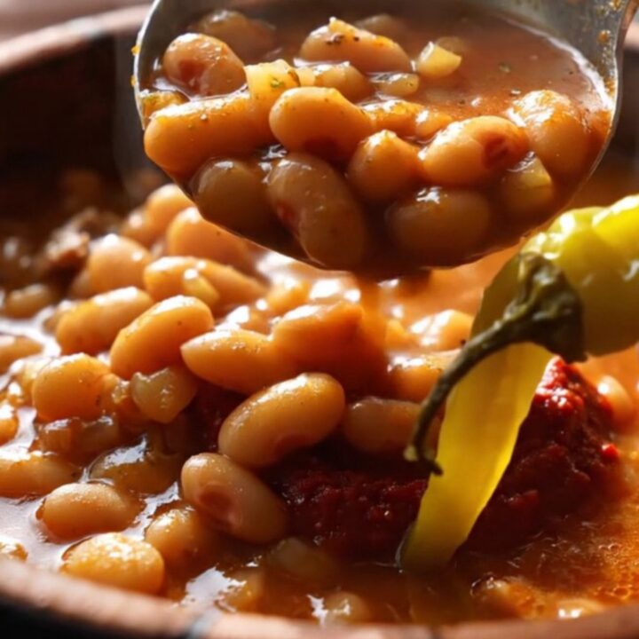 A clay pot of Turkish kuru fasulye with white beans and pastırma in rich red sauce, served over butter rice pilaf