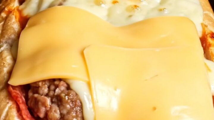 Giant stuffed mozzarella and pepperoni meatball sub with blistered provolone cheese, cut to show molten cheese pull.