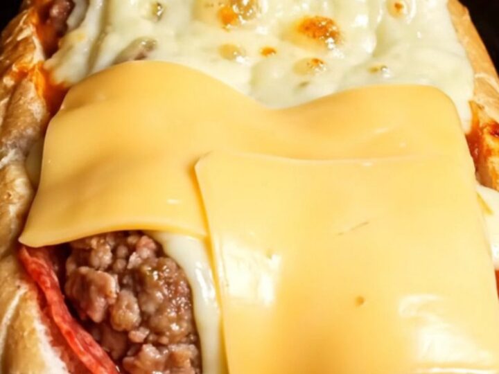 Giant stuffed mozzarella and pepperoni meatball sub with blistered provolone cheese, cut to show molten cheese pull.
