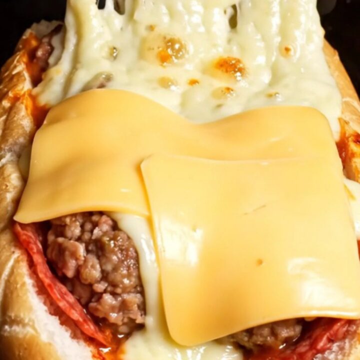 Giant stuffed mozzarella and pepperoni meatball sub with blistered provolone cheese, cut to show molten cheese pull.