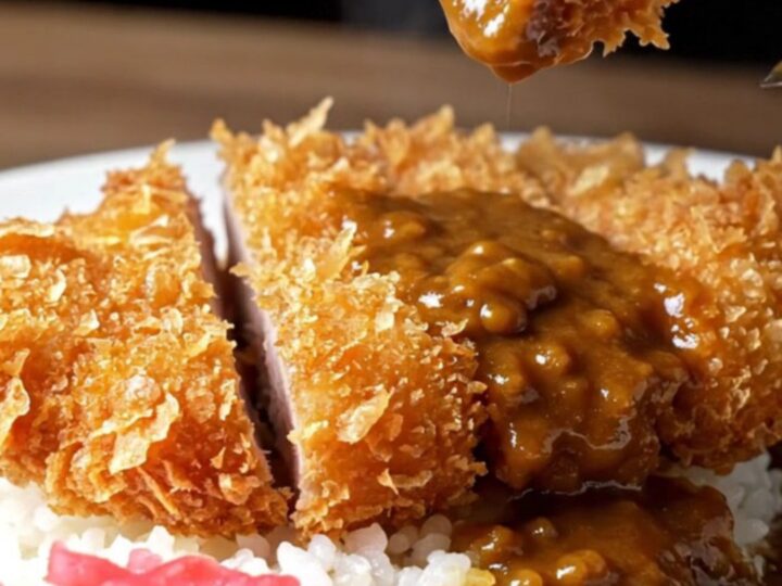 Sliced pork katsu curry over rice with pickled radish